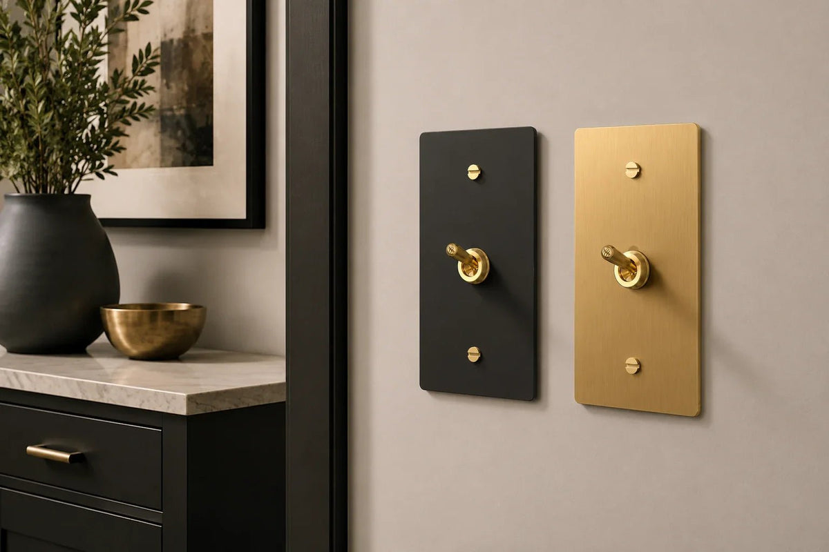 Modern brass and black toggle light switches installed on a neutral wall in a luxury contemporary interior with warm lighting, matte black cabinetry, and minimalist designer decor.