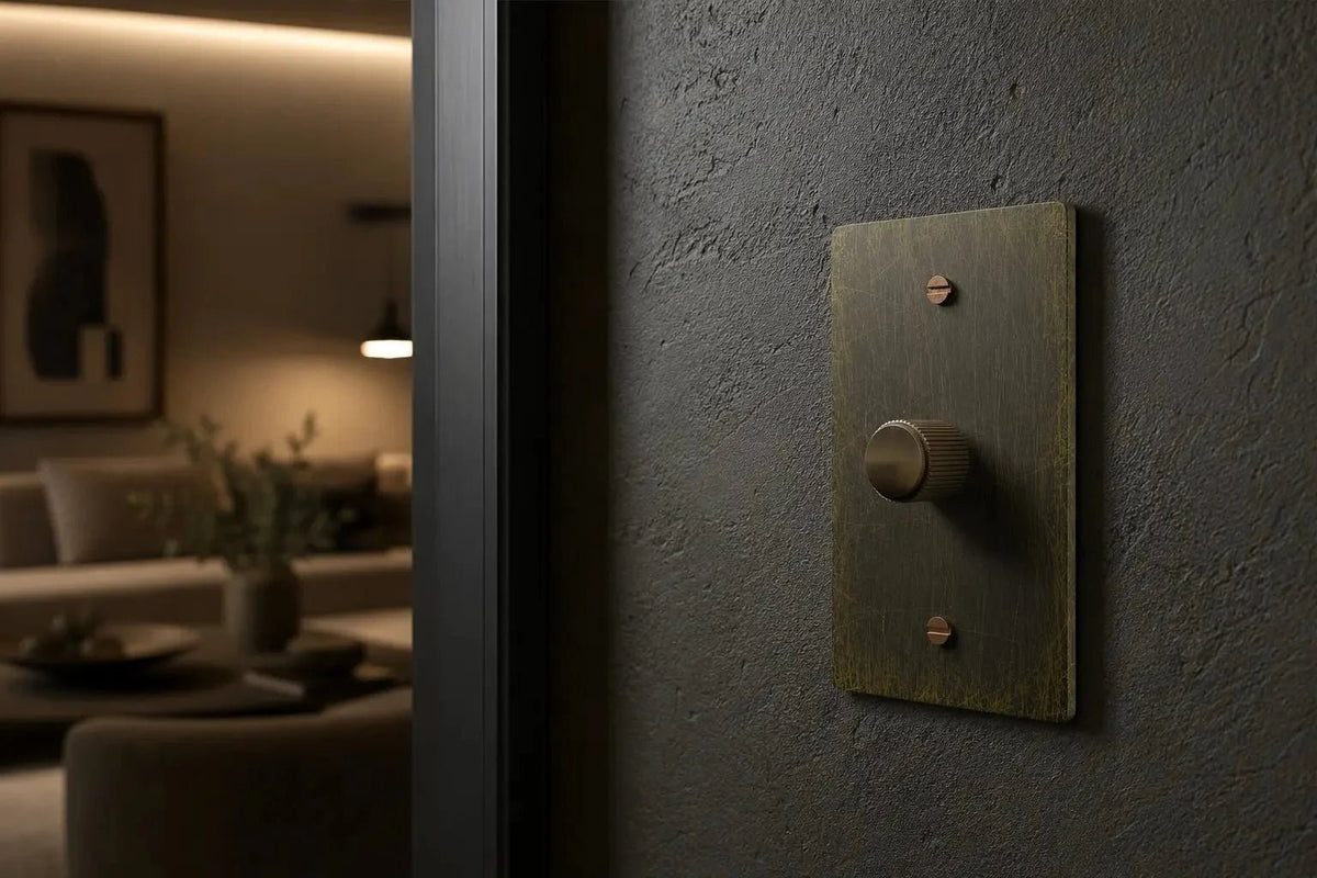 Luxury antique brass dimmer switch installed on a dark textured wall in a modern high-end living room interior with warm ambient lighting and premium minimalist decor.