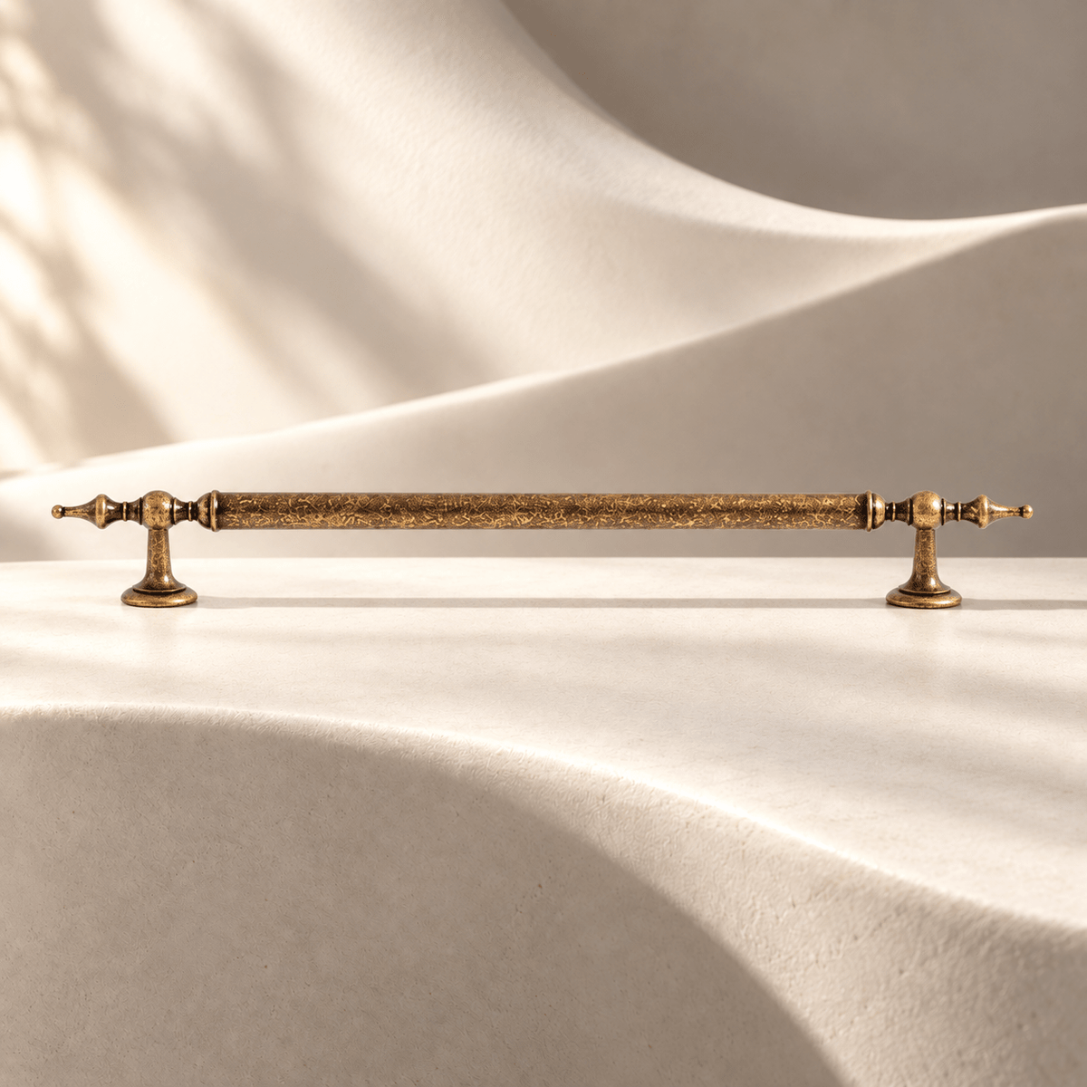 Aged antique brass cabinet pull — 224 mm on warm ivory stone