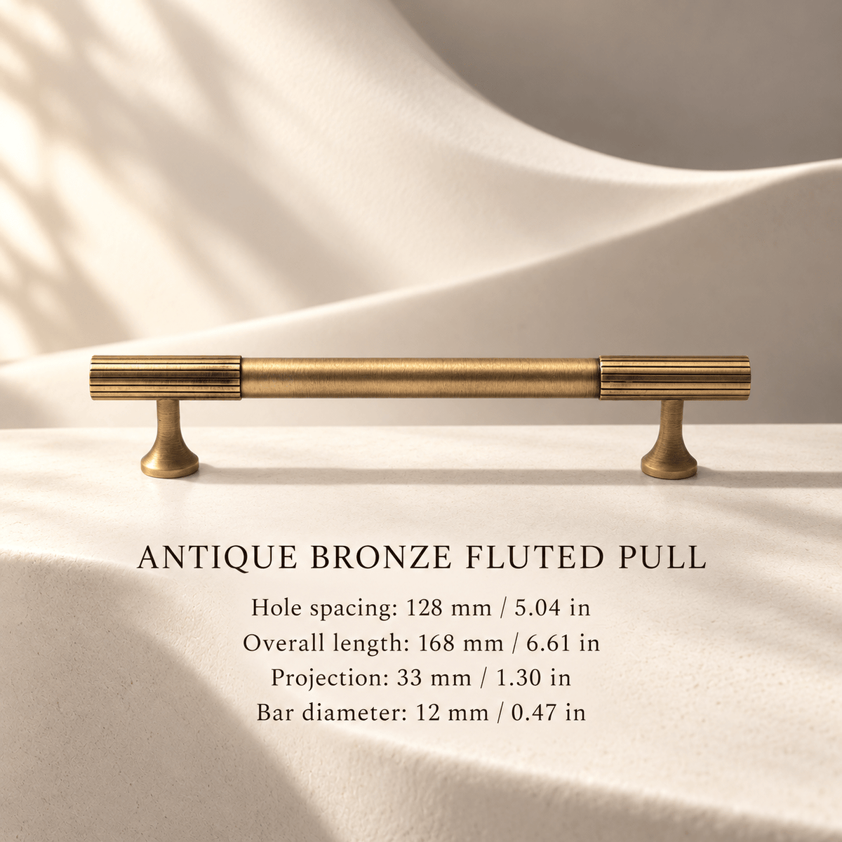 Antique bronze fluted pull in ivory studio. Hole spacing: 128 mm / 5.04 in; Overall length: 168 mm / 6.61 in; Projection: 33 mm / 1.30 in; Bar diameter: 12 mm / 0.47 in.