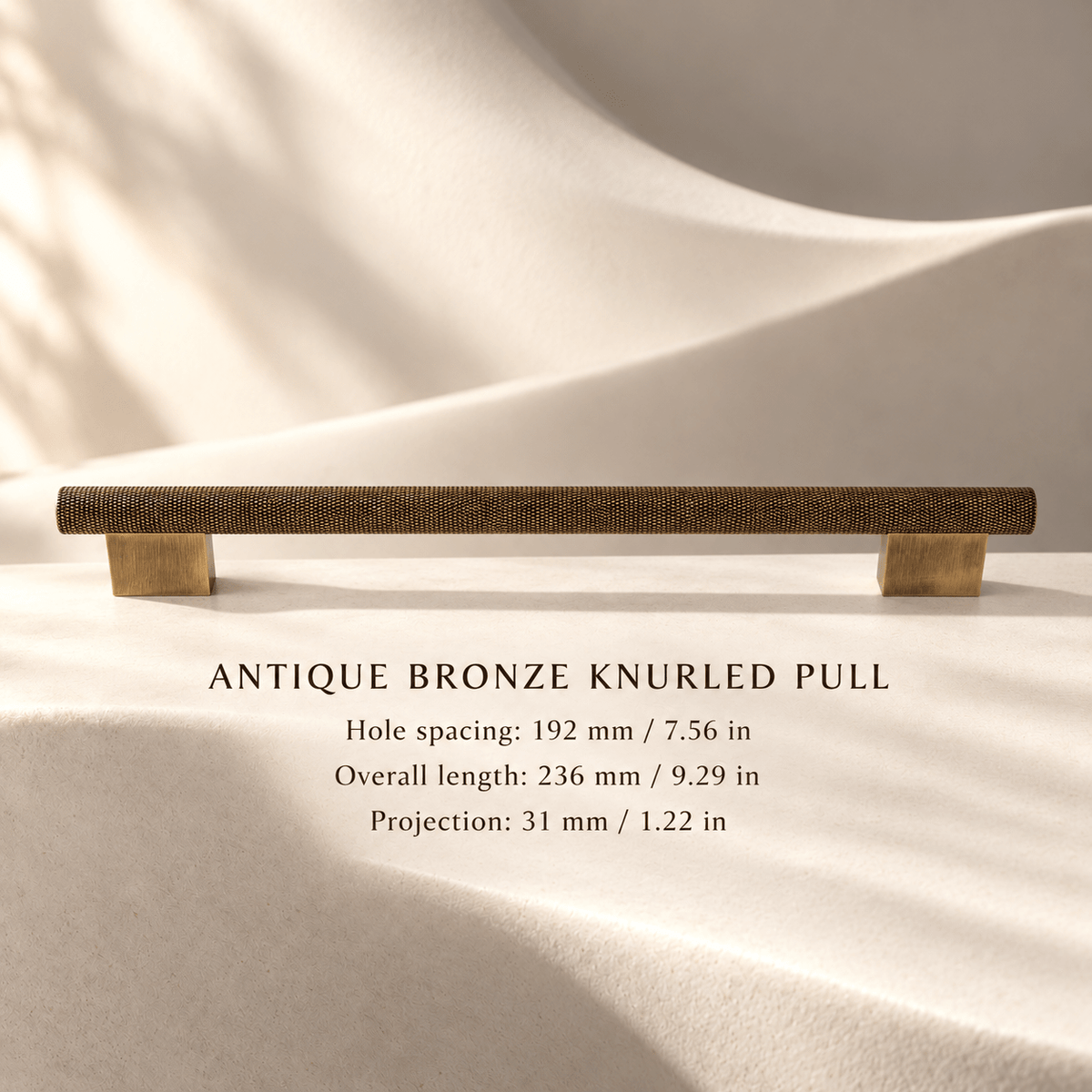 Antique bronze knurled cabinet pull, 192 mm hole spacing, with individual mm and inch measurements in an ivory stone studio