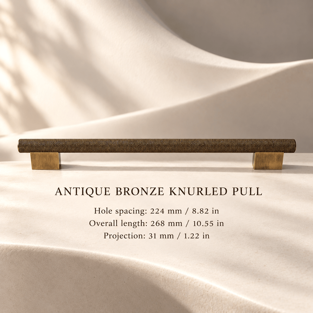 Antique bronze knurled cabinet pull, 224 mm hole spacing, with individual mm and inch measurements in an ivory stone studio