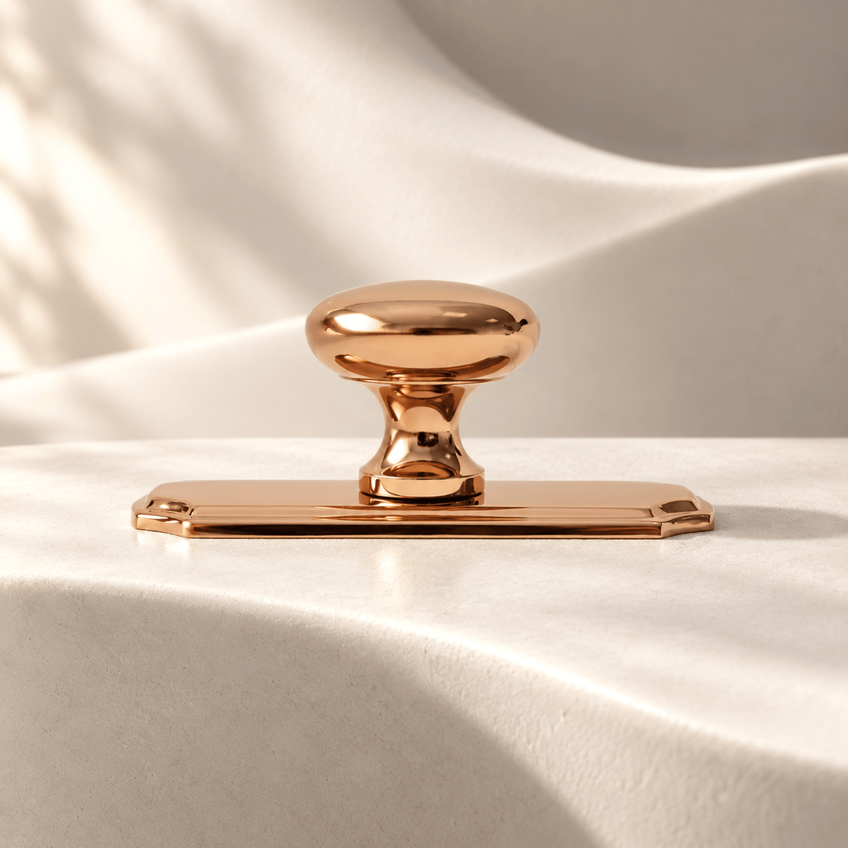 Rose gold knob with 70 × 25 mm decorative backplate — warm ivory stone studio