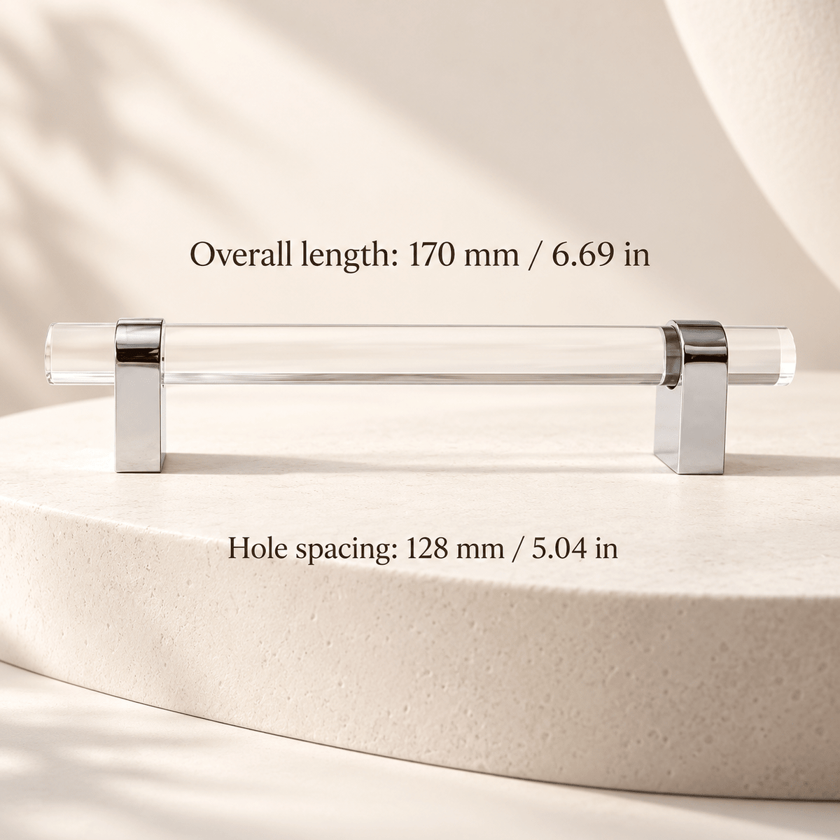 Clear acrylic pull with chrome feet in ivory studio. Hole spacing: 128 mm / 5.04 in; Overall length: 170 mm / 6.69 in