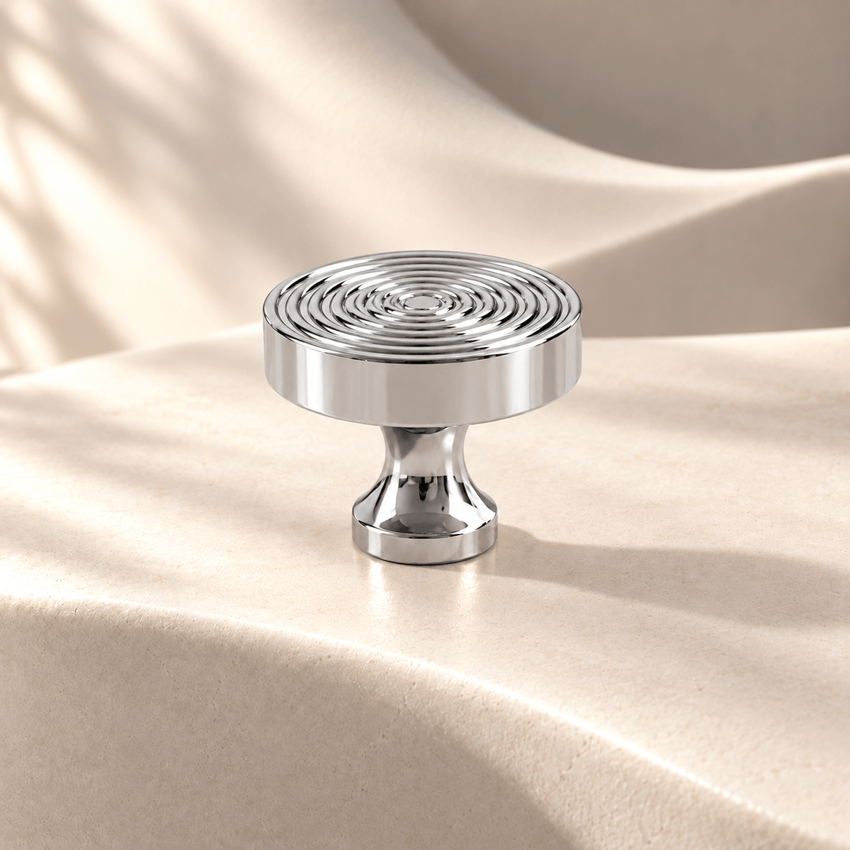 Concentric-ring cabinet knob in chrome on warm ivory stone