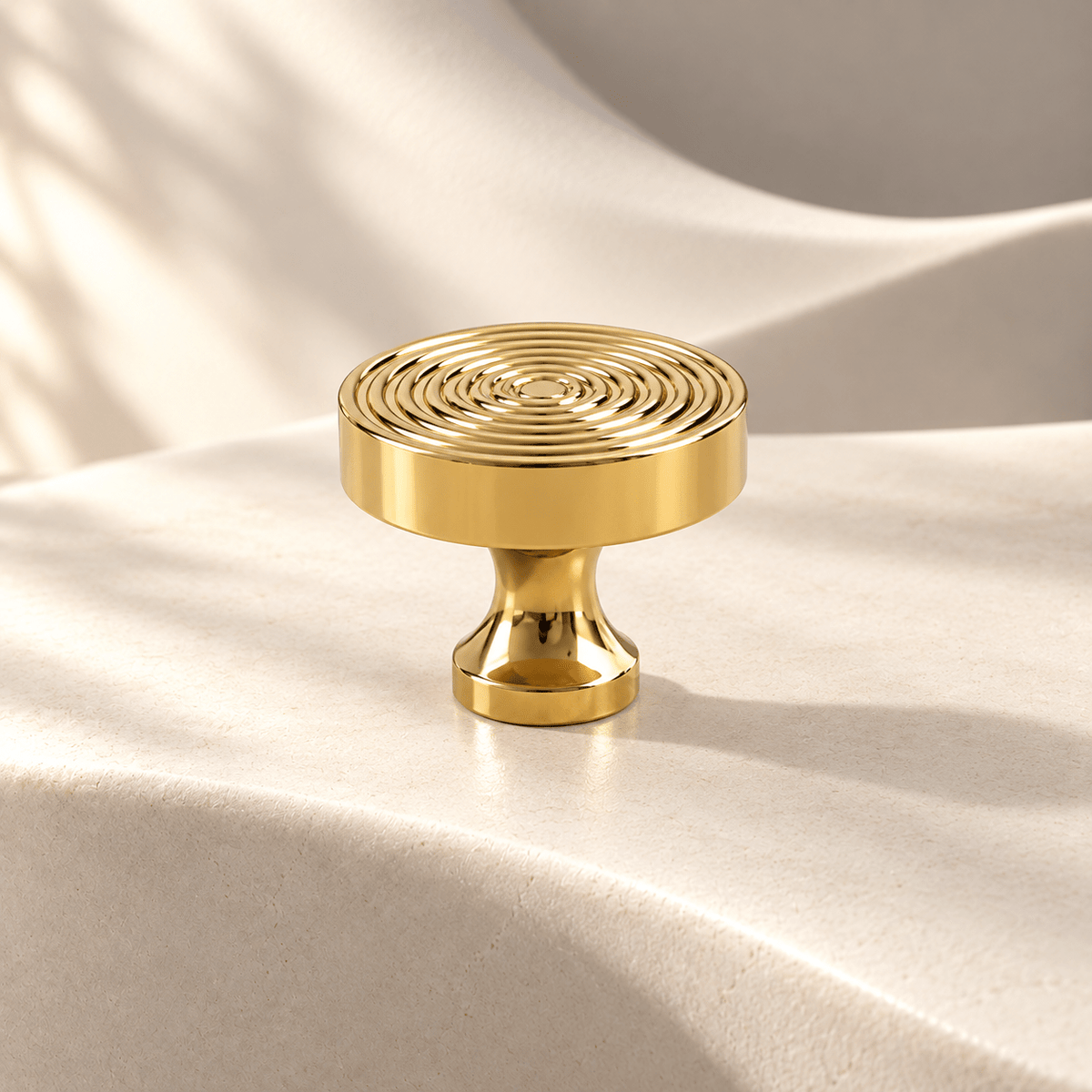 Concentric-ring cabinet knob in bright gold on warm ivory stone