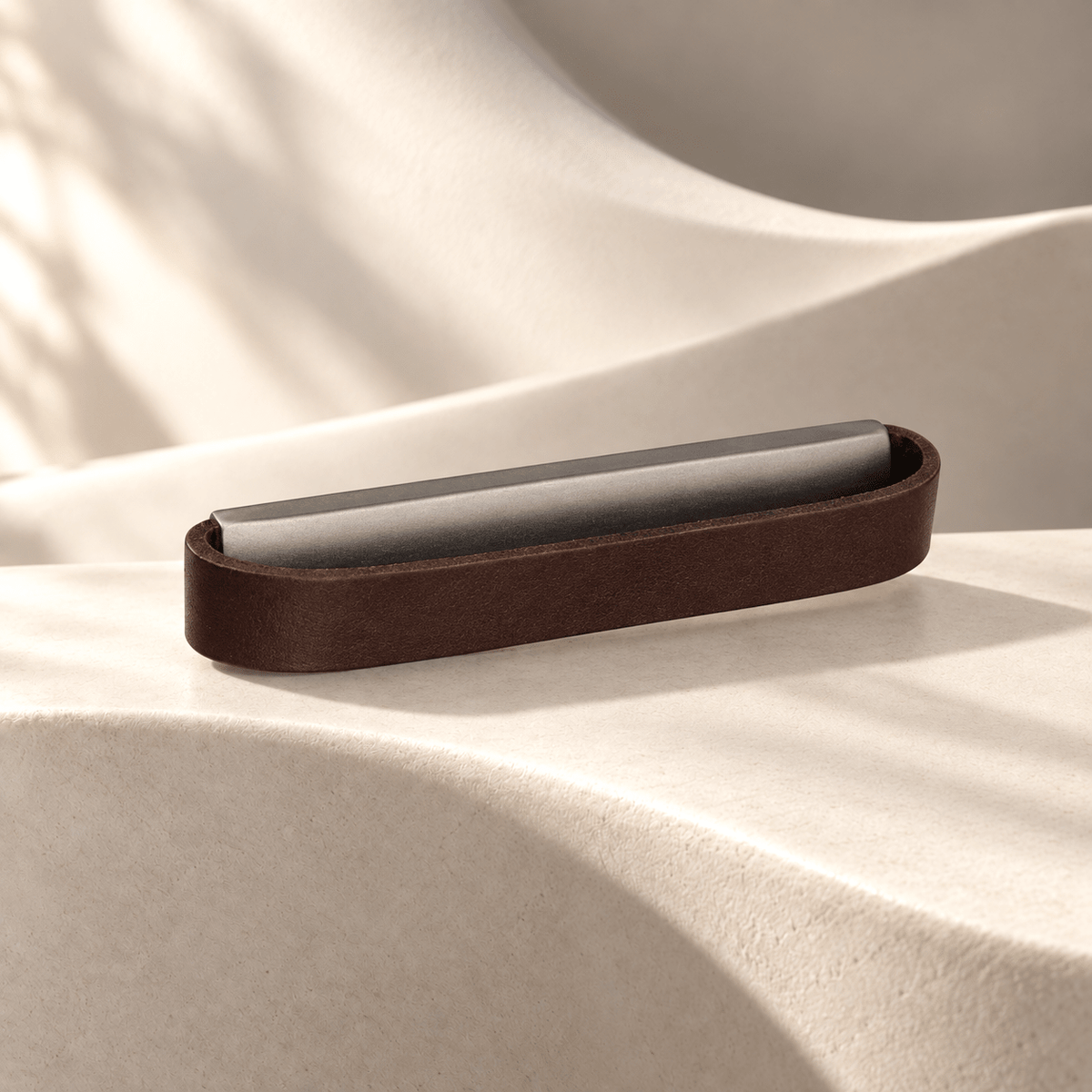 Dark brown leather cabinet pull with graphite-tone inner bar on ivory stone