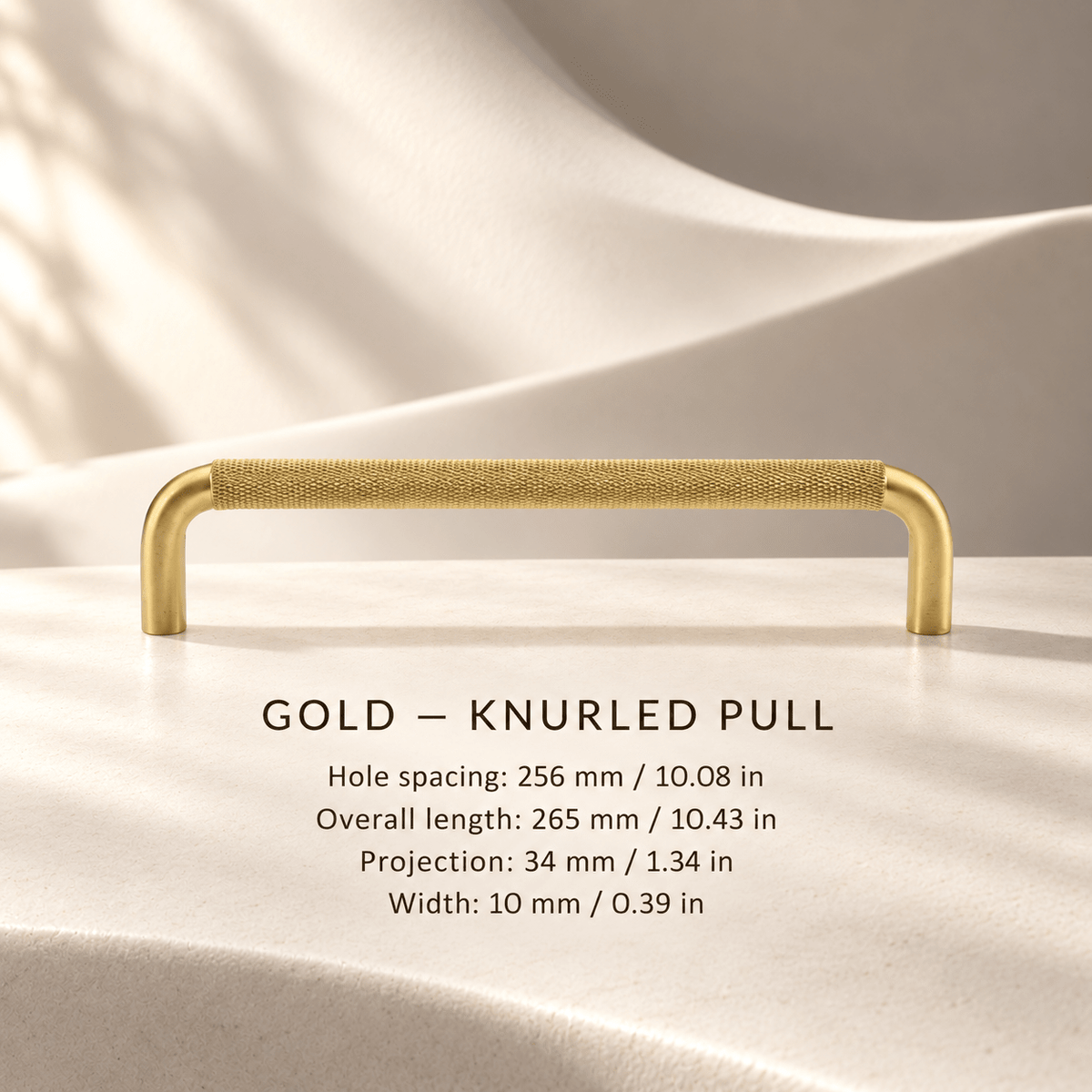 Gold knurled cabinet pull in ivory studio. Hole spacing: 256 mm / 10.08 in; Overall length: 265 mm / 10.43 in; Projection: 34 mm / 1.34 in; Width: 10 mm / 0.39 in
