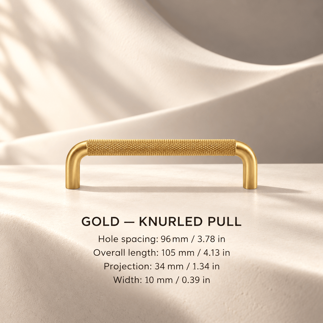 Gold knurled cabinet pull in ivory studio. Hole spacing: 96 mm / 3.78 in; Overall length: 105 mm / 4.13 in; Projection: 34 mm / 1.34 in; Width: 10 mm / 0.39 in