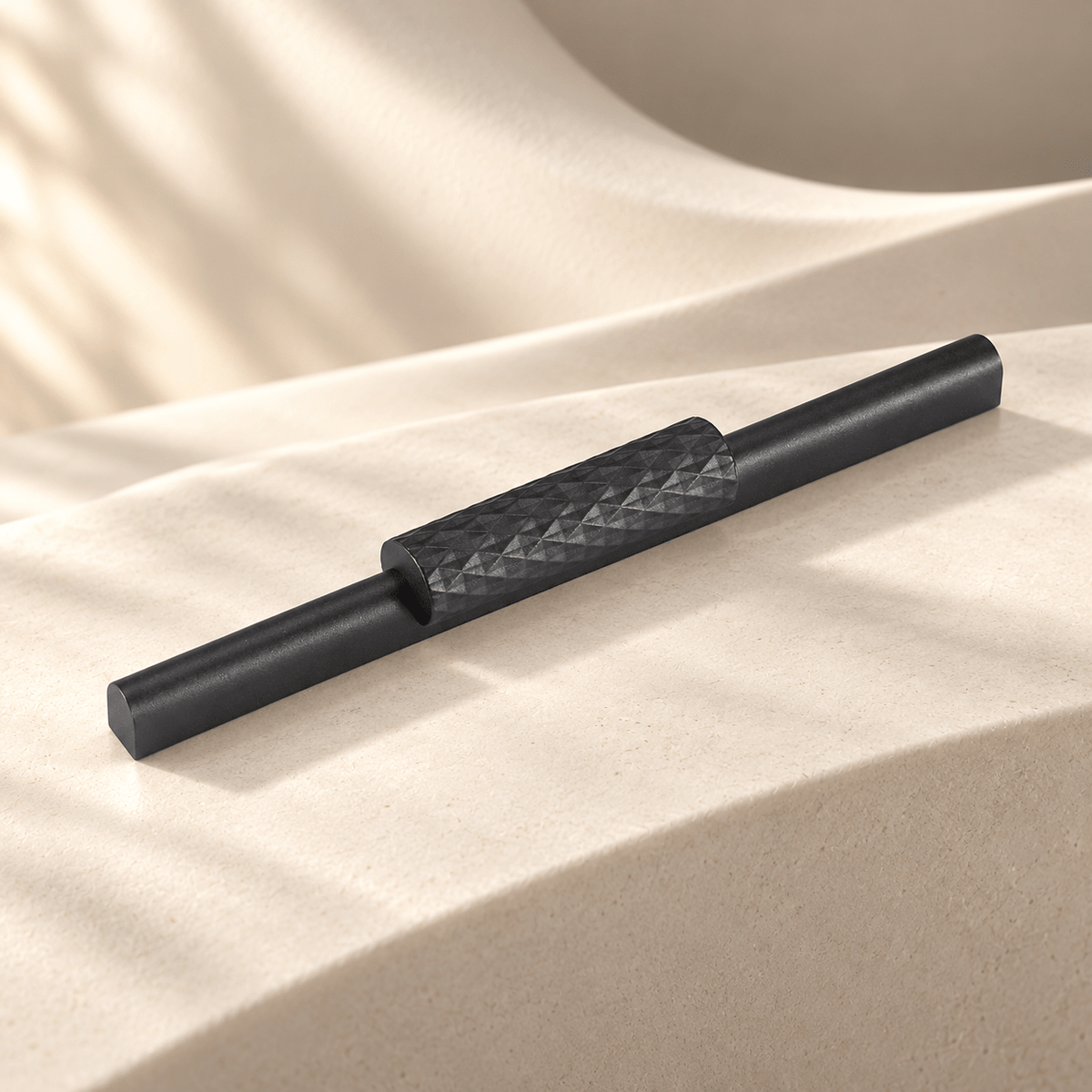 Gray faceted aluminum cabinet handle in a warm ivory stone studio