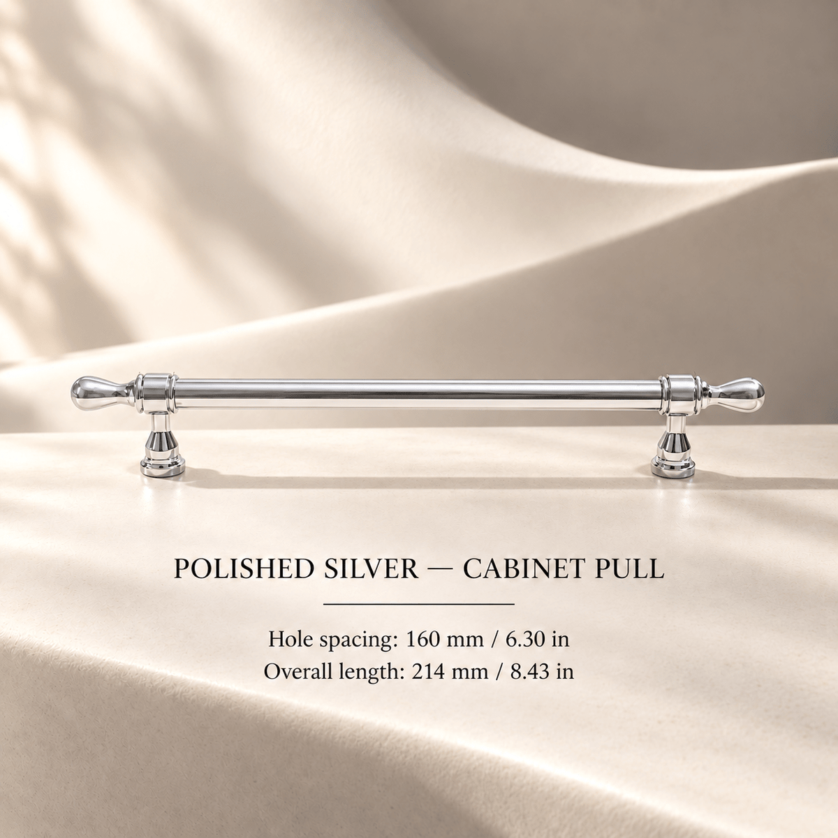 Chrome French-style cabinet pull in ivory studio. Hole spacing: 160 mm / 6.30 in; Overall length: 214 mm / 8.43 in.
