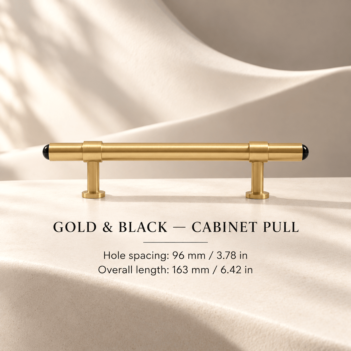 Gold cabinet pull with black end caps in ivory studio. Hole spacing: 96 mm / 3.78 in; Overall length: 163 mm / 6.42 in