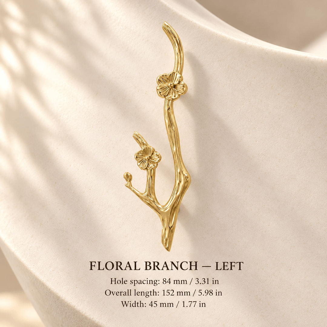 Gold floral branch cabinet pull, left, in ivory studio. Hole spacing: 84 mm / 3.31 in; Overall length: 152 mm / 5.98 in; Width: 45 mm / 1.77 in