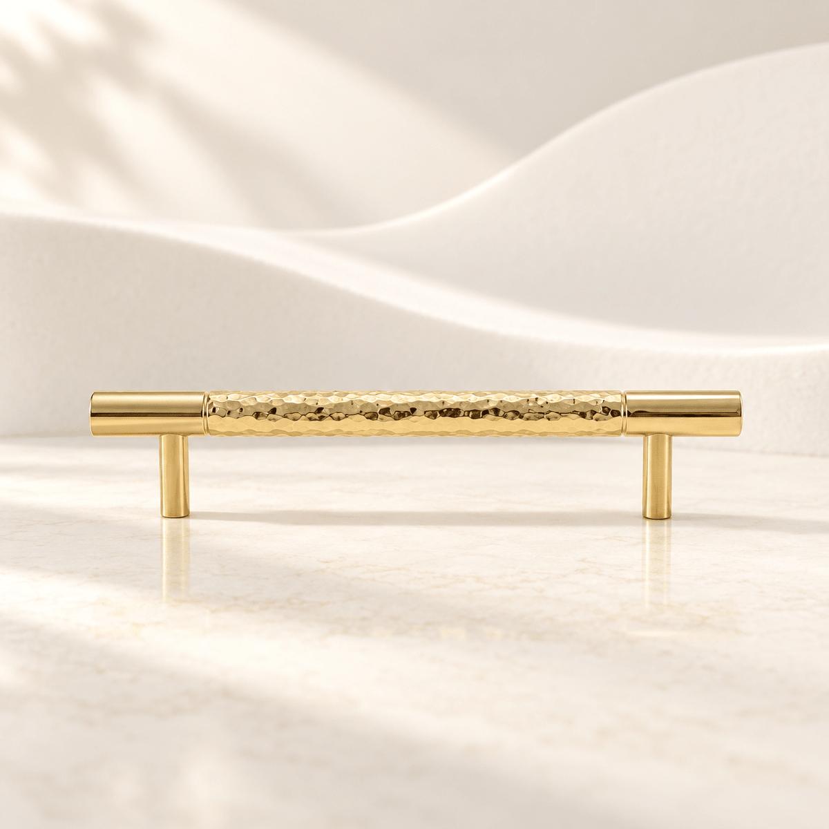 Hammered gold brass cabinet pull with 128 mm (5.04 in) hole spacing on ivory stone