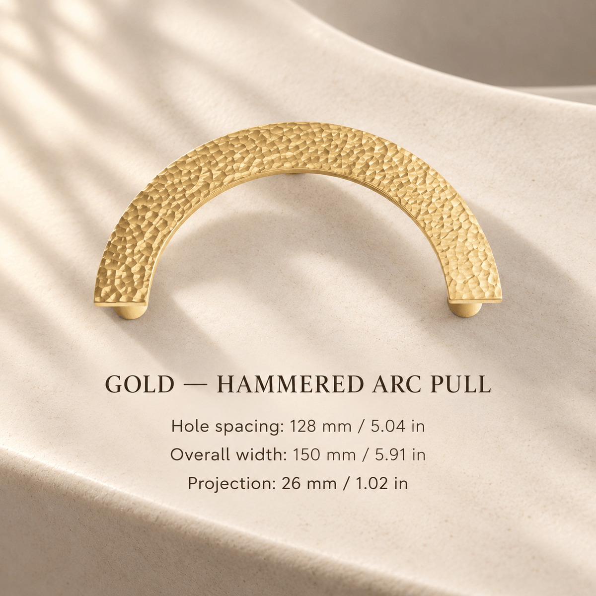 Hammered gold semicircular cabinet pull in ivory studio. Hole spacing: 128 mm / 5.04 in; Overall width: 150 mm / 5.91 in; Projection: 26 mm / 1.02 in