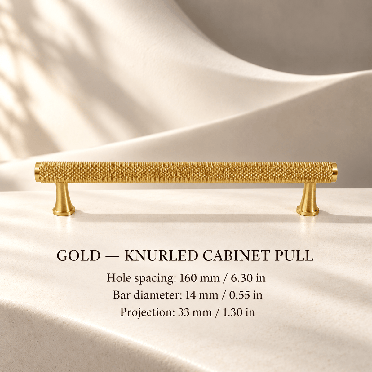 Gold knurled cabinet pull with flared feet in ivory studio. Hole spacing: 160 mm / 6.30 in; Bar diameter: 14 mm / 0.55 in; Projection: 33 mm / 1.30 in