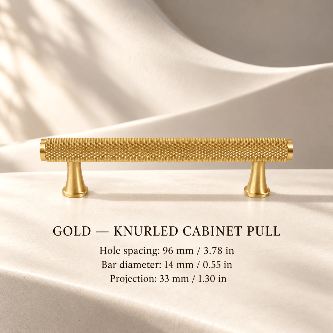 Gold knurled cabinet pull with flared feet in ivory studio. Hole spacing: 96 mm / 3.78 in; Bar diameter: 14 mm / 0.55 in; Projection: 33 mm / 1.30 in