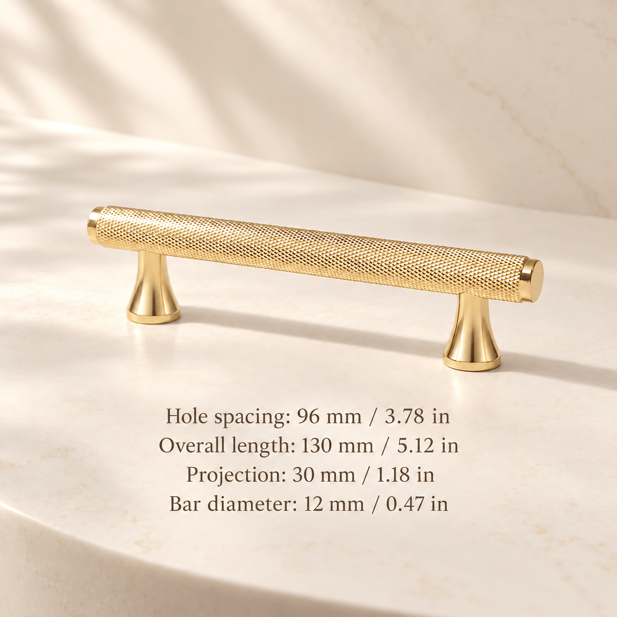 Gold knurled cabinet pull with flared feet in ivory studio. Hole spacing: 96 mm / 3.78 in; Overall length: 130 mm / 5.12 in; Projection: 30 mm / 1.18 in; Bar diameter: 12 mm / 0.47 in