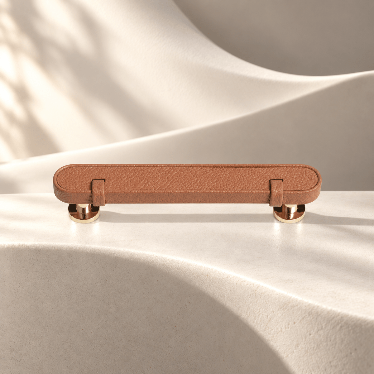 Tan — 96 mm CTC leather cabinet pull on warm ivory stone