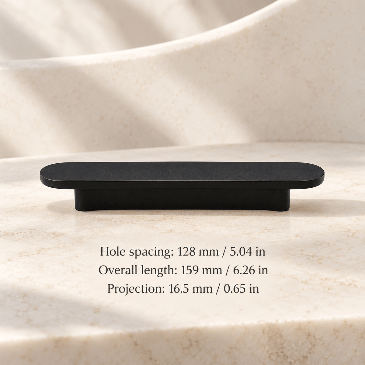 Matte black low-profile oval cabinet pull in ivory studio. Hole spacing: 128 mm / 5.04 in; Overall length: 159 mm / 6.26 in; Projection: 16.5 mm / 0.65 in