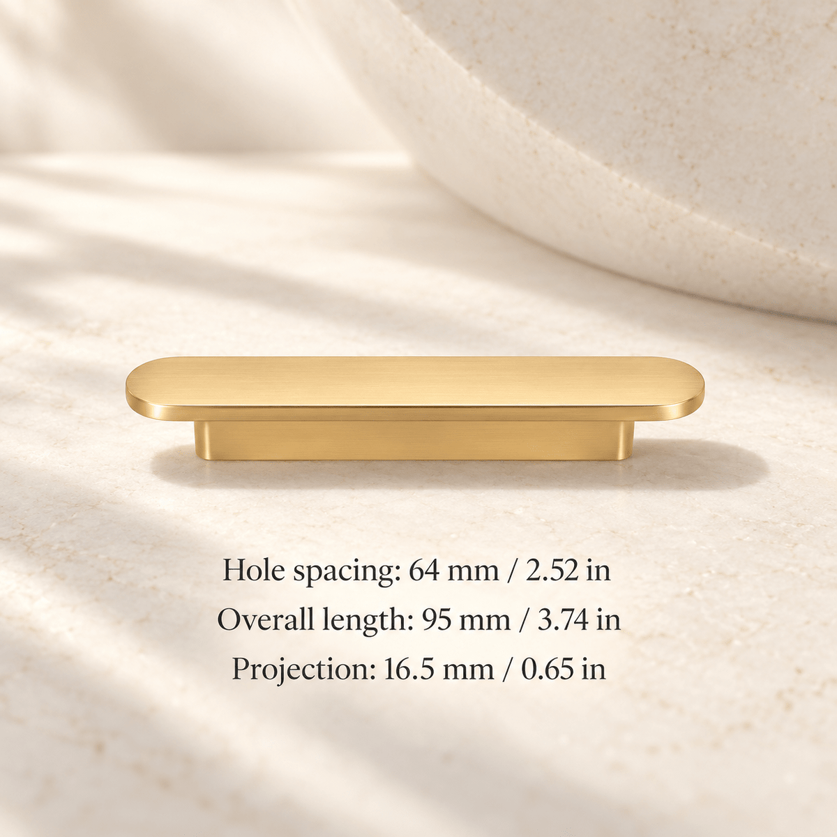 Gold low-profile oval cabinet pull in ivory studio. Hole spacing: 64 mm / 2.52 in; Overall length: 95 mm / 3.74 in; Projection: 16.5 mm / 0.65 in