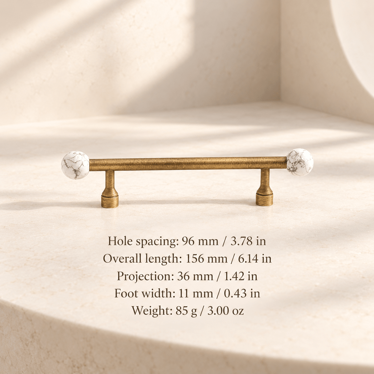 Antique gold cabinet pull with white patterned ball ends in ivory studio. Hole spacing: 96 mm / 3.78 in; Overall length: 156 mm / 6.14 in; Projection: 36 mm / 1.42 in; Foot width: 11 mm / 0.43 in; Weight: 85 g / 3.00 oz