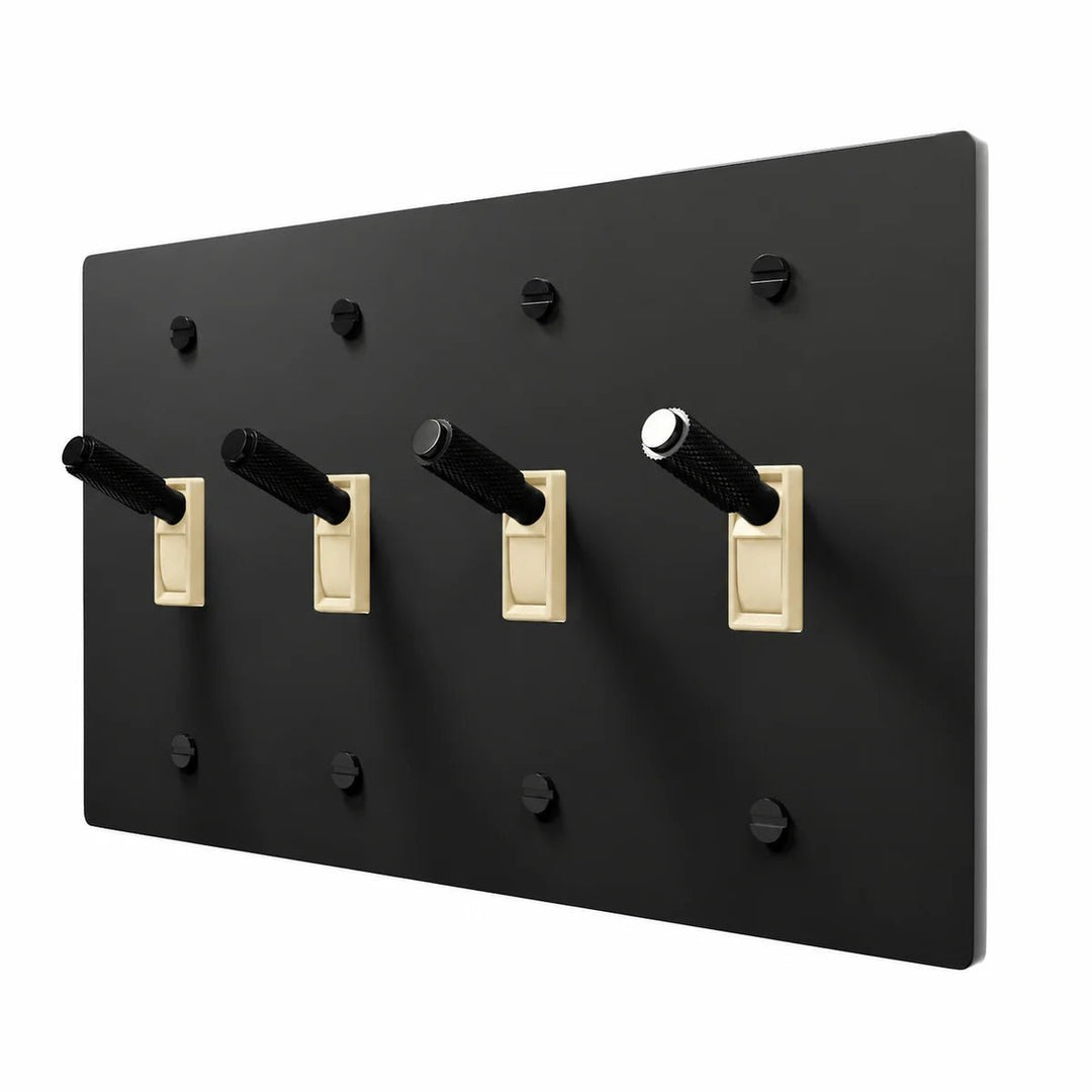 PlatePrestige Brass Toggle Switch 4-Gang in All‑Black with ivory toggle frames, angled view