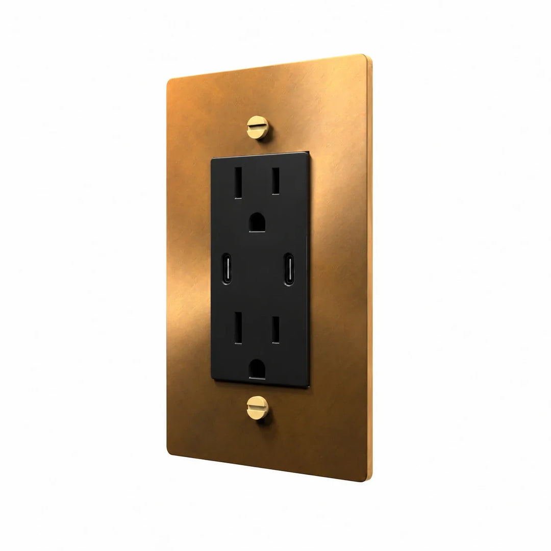 Angle view of PlatePrestige dual USB-C electrical outlet, unlacquered aged brass wall plate with black receptacle and coordinated screws