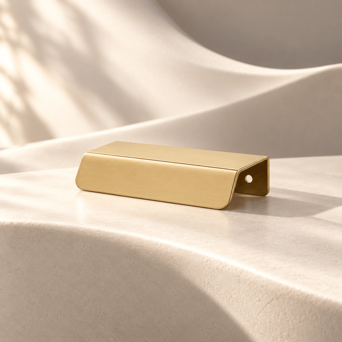 Satin gold 64 mm CTC cabinet edge pull on warm ivory stone
