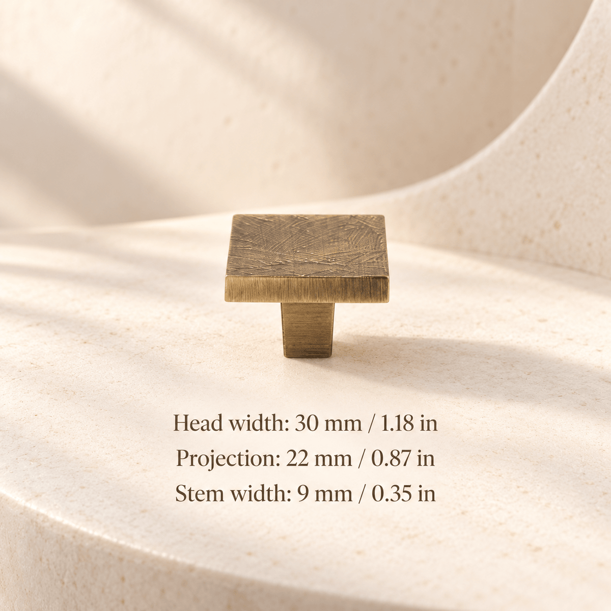 Antique bronze textured flat cabinet knob in ivory studio. Head width: 30 mm / 1.18 in; Projection: 22 mm / 0.87 in; Stem width: 9 mm / 0.35 in